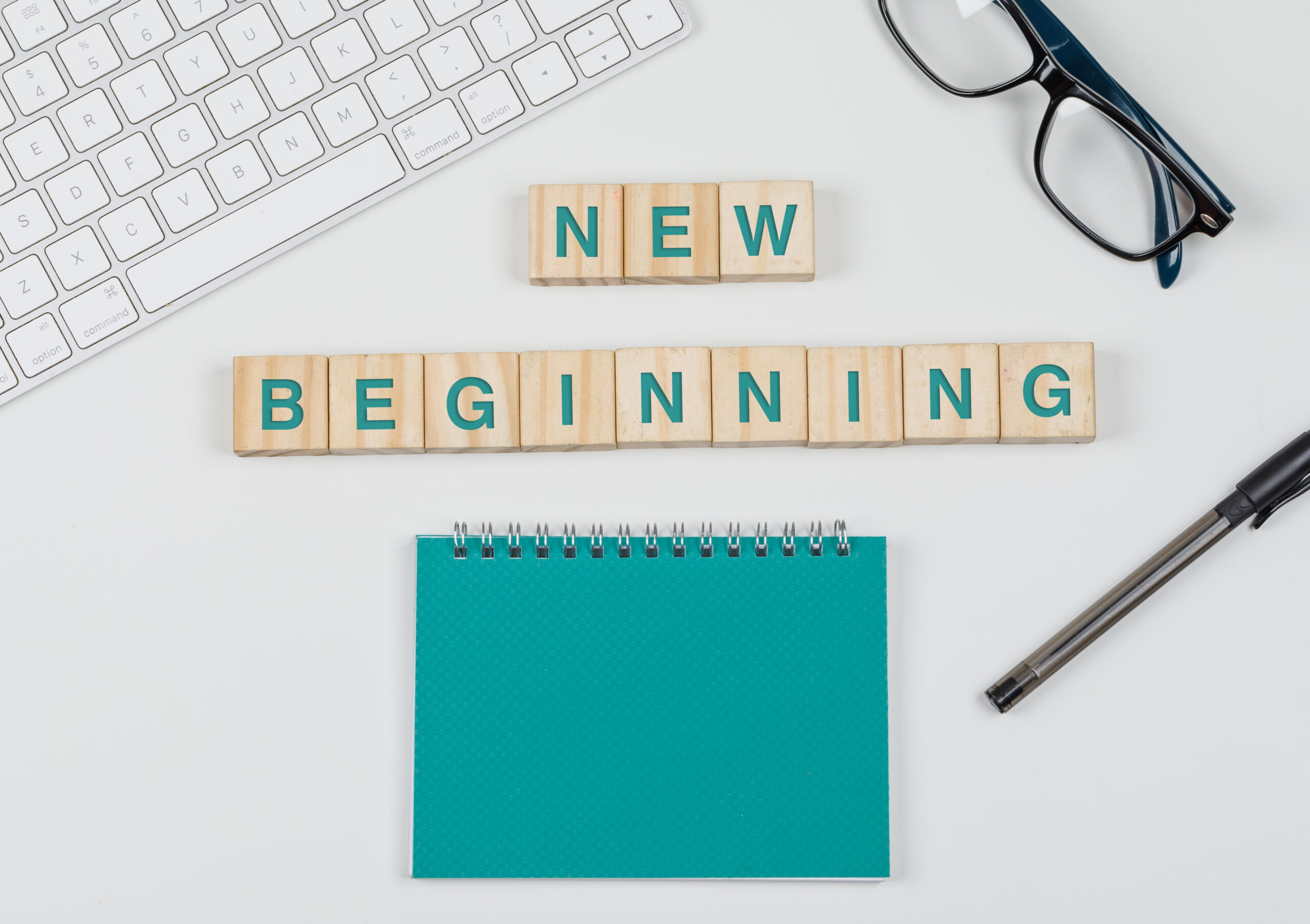 new start business concept with wooden blocks glasses keyboard pen notebook white background flat lay scaled