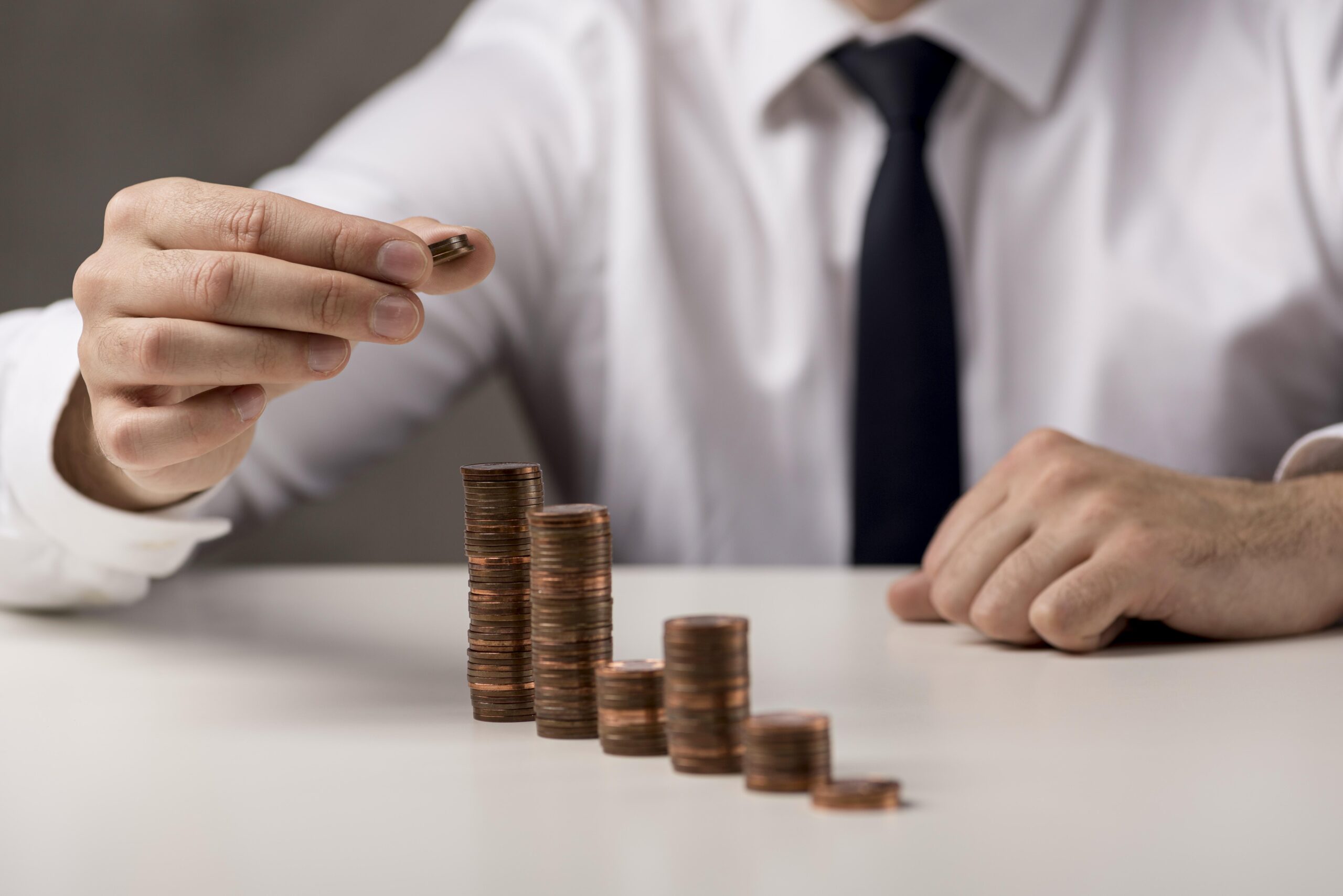 businessman adding coin stack scaled